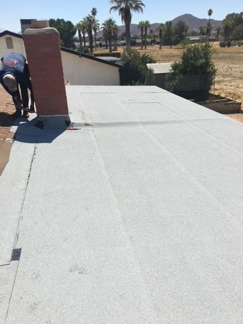 Torch-down flat roof being finished around a brick chimney by a Baker Roofing worker